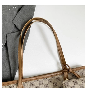 Close-up of brown monogram tote bag with leather straps and mini pouch charm