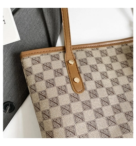 Close-up of vintage canvas tote bag showing retro patterns and leather strap detail