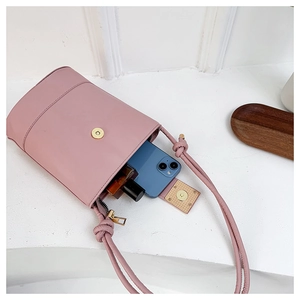 Detailed interior of a pink bucket bag showing storage for phone and cosmetics