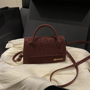 Sac bandoulière bordeaux imprimé léopard posé sur un tissu en soie blanche élégant