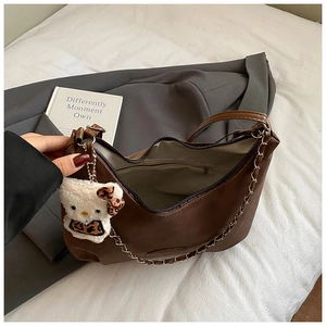 Detailed interior of a brown leather shoulder bag featuring a chain strap and cat plushie
