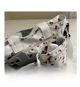 Detailed view of the white canvas tote bag with cherry print and multi-zipper pockets