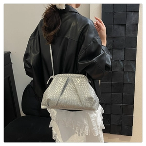 Close-up of metallic silver shell bag with pleated texture and embossed crocodile pattern