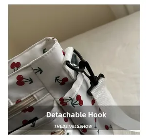 Detail of the detachable black plastic hook and woven strap on a cherry print handbag