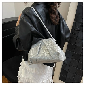 Close-up of metallic silver woven shell bag with thin shoulder strap on a model
