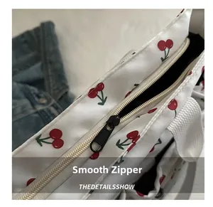 Detail shot of the smooth black zipper closure on a white cherry print tote bag