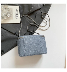 Close-up of blue denim texture and gold chain strap on stylish shoulder bag