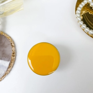 Foldable circular phone grip in ginger yellow glaze finish with refined gold metal frame