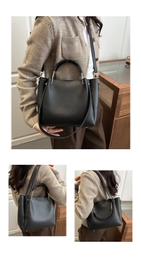 Detail der schwarzen Tote-Bag aus Leder mit goldenen Metallgriffen und langem Schultergurt
