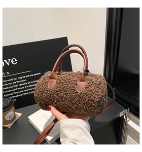 Détail d'un sac boston marron en peluche bouclée avec poignées en cuir et bandoulière