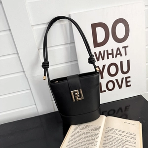 Minimalist black leather bucket bag with large gold geometric buckle and knotted strap