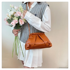 Close-up of brown woven shell bag with pleated cloud design and shoulder strap