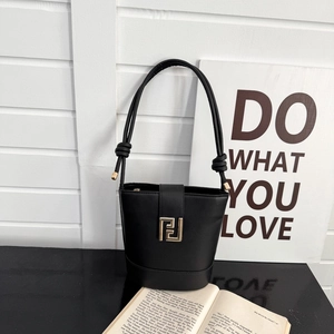 Minimalist black bucket bag with gold geometric buckle and knotted shoulder strap detail