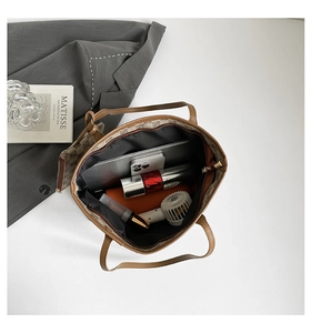Spacious interior of brown tote bag holding a laptop, phone, and daily essentials
