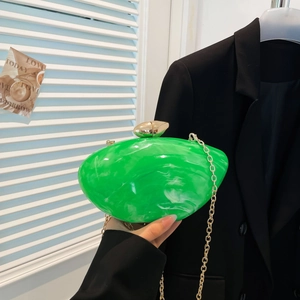 Green marble acrylic evening clutch bag with gold chain strap held by model in black suit