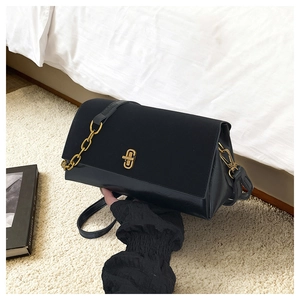Detail of elegant black shoulder bag featuring gold clasp and metallic chain strap