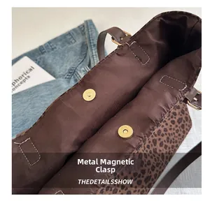 Detail of leopard print tote bag featuring magnetic gold hardware and dark brown lining
