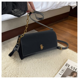 Detail of black crossbody bag with gold cross lock and elegant metal chain strap