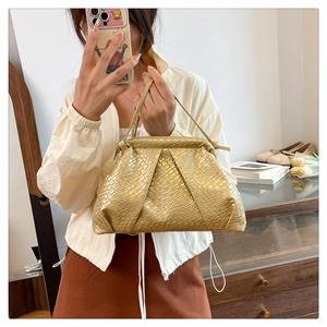 Detail of golden woven texture and cloud-like pleated design on the shell handbag