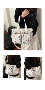Detail view of cherry print canvas tote bag with front zip pockets and side compartments