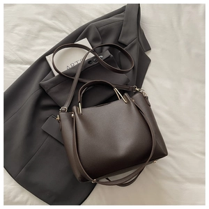 Detail of dark brown leather bucket bag with gold handle and protective metal feet