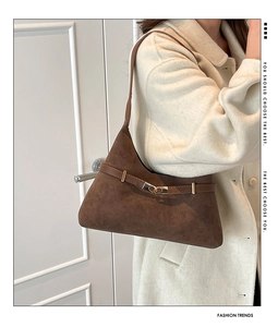 Brown suede shoulder bag with gold metal buckle paired with a cream wool coat