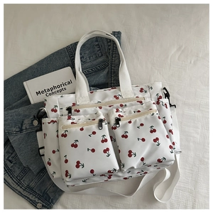Close-up of white cherry print tote bag featuring multiple front zipper pockets