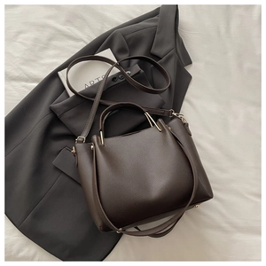 Detail of dark brown lychee-patterned tote bag with golden hardware and adjustable strap