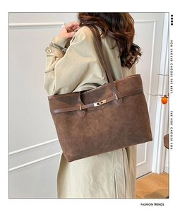 Close-up of brown suede tote bag with gold buckle detail on a model in a trench coat