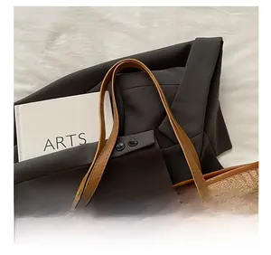 Dettaglio borsa tote in velluto a coste marrone con manici in pelle e rivetti in metallo