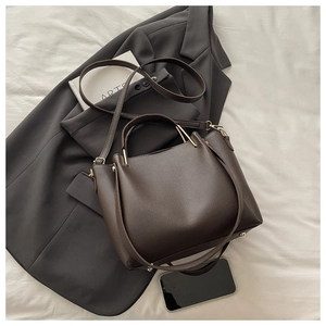 Detailed close-up of dark brown lychee texture leather handbag with golden metal hardware