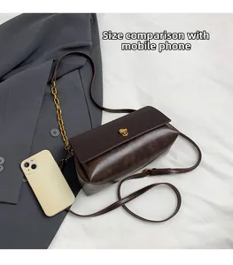 Deep brown crossbody bag with gold lock and phone shown for size comparison