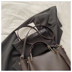Detail of dark brown lychee grain leather texture with gold metal hardware on tote bag