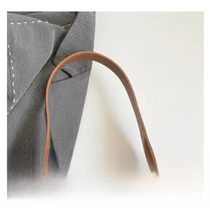 Detailed close-up of brown leather handbag handle with fine stitching and soft texture