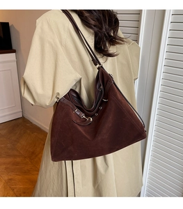 Dettaglio della grande borsa tote in pelle scamosciata marrone scuro con anelli metallici