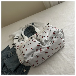 Detail of white nylon tote bag with cherry print and multiple zipper pockets