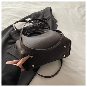 Detail shot of deep brown lychee grain leather handbag featuring protective bottom metal studs