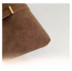 Macro shot of brown suede tote bag featuring premium leather strap and golden metal buckle