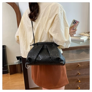 Detail of black woven leather handbag with pleated design in a home setting