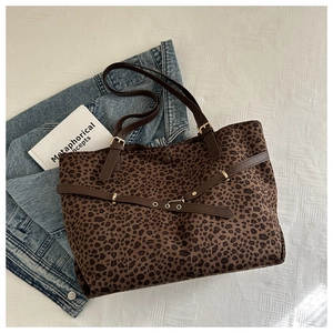 Close-up of leopard print canvas tote bag with brown leather handles and metal buckle detail