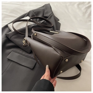 Detail of dark brown pebble leather bucket bag showing gold base studs and texture