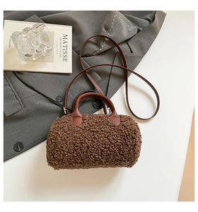 Détail d'un sac cylindrique en fourrure marron avec poignées en cuir sur fond blanc