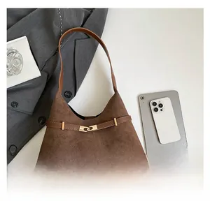 Detailed close-up of brown suede tote bag with leather strap and golden metal buckle