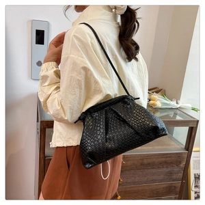 Close-up of black woven shell bag featuring a soft pleated closure and slim shoulder strap