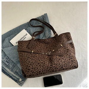 Flat lay of leopard print tote bag with brown leather straps and casual lifestyle props