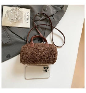 Vue de dessus d'un sac cylindrique en peluche marron avec anses en cuir et téléphone
