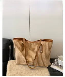 Detail of brown corduroy tote bag with leather trim on a cozy coffee shop table