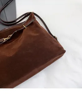 Dettaglio della borsa tote in pelle scamosciata marrone con tracolla e fibbia d'oro