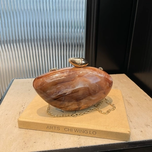 Artistic amber marble resin clutch bag with gold chain strap and pebble design