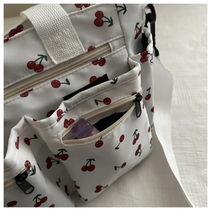Close-up of white cherry print nylon bag with multiple functional zipper pockets